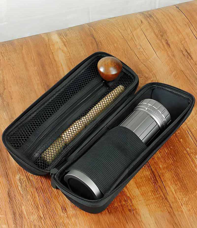A portable coffee grinder packed in a travel bag next to a passport