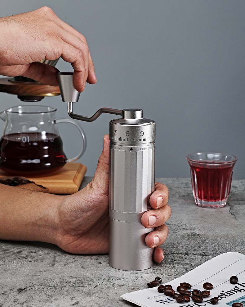 Hand coffee grinder producing rich golden crema for an espresso shot.